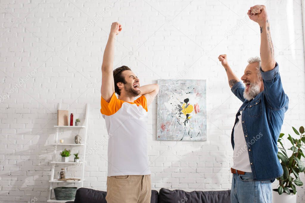 Excited father and young son showing yes gesture at home 