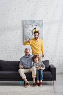 Ailesi ve şok olmuş çocuğu oturma odasında kanepede balık tutmaca oynuyorlar. 