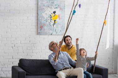 Excited kid playing toy fishing with father and grandfather  clipart