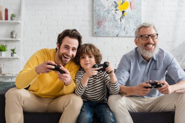 KYIV, UKRAINE - 12 Nisan 2021: Erkekler ve çocuklar evde video oyunu oynuyorlar 