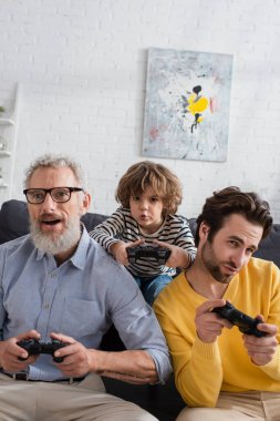 KYIV, UKRAINE - 12 Nisan 2021: Ebeveynler ve büyükbabalar evde çocuklarla video oyunu oynuyorlar 