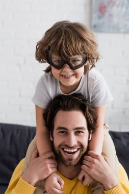 Smiling kid in aviator goggles hugging father  clipart