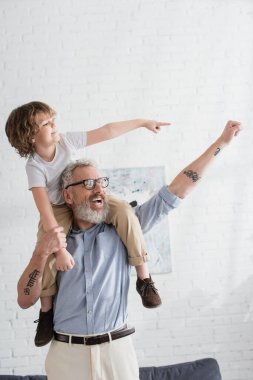 Excited boy and grandfather gesturing at home  clipart