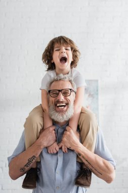 Heyecanlı çocuk gülümseyen büyükbabaya sarılıyor. 