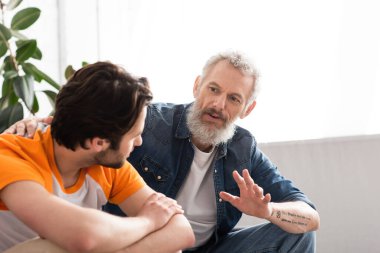 Mature father calming sad son at home  clipart