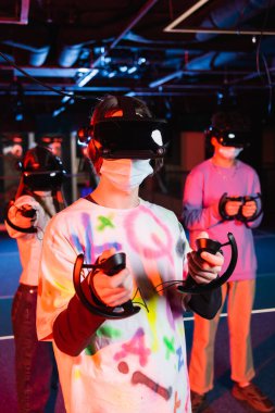 VR kulaklıklı genç oyuncular oyun odasında eğleniyorlar.