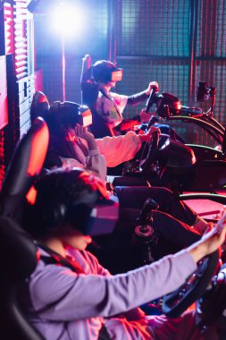 teenagers in vr headsets playing racing game in car simulators clipart