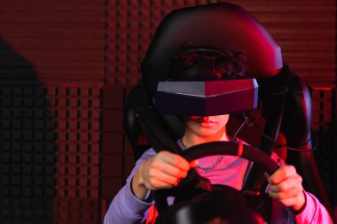 teenage guy in virtual reality headset racing on car simulator clipart