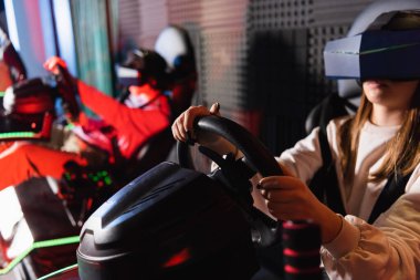 friends in vr headsets playing racing game on car simulators, blurred foreground clipart