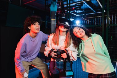 VR oyun sahasında kameraya gülümseyen neşeli çoklu etnik arkadaşlar