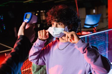 Genç oyuncu, tıbbi maskeyi kontrol cihazının yanında pirometreyle ayarlıyor.