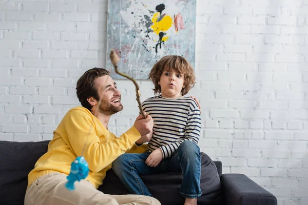 Cheerful Father Sitting Excited Son Toy Fishing Rod Blurred Foreground — Stock Photo, Image