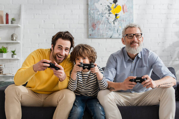 КИЕВ, УКРАИНА - 12 апреля 2021 года: Веселые родители и мальчик играют в видеоигры в гостиной 