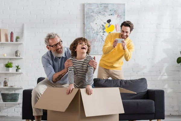 Mature Man Hugging Cheerful Grandson Cardboard Box Son Taking Photo — Stock Photo, Image