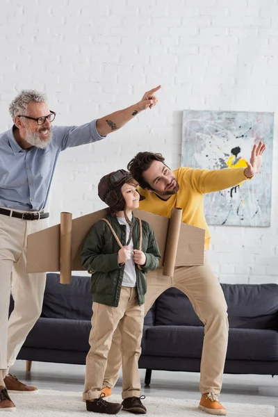 Lächelnder Vater Und Großvater Zeigen Auf Kind Fliegerkostüm — Stockfoto