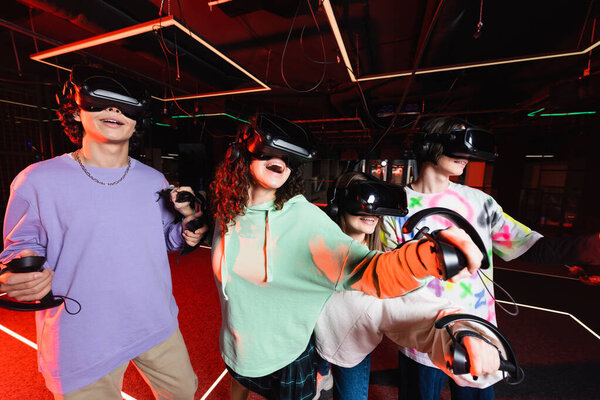 astonished multiethnic friends having fun in vr game zone