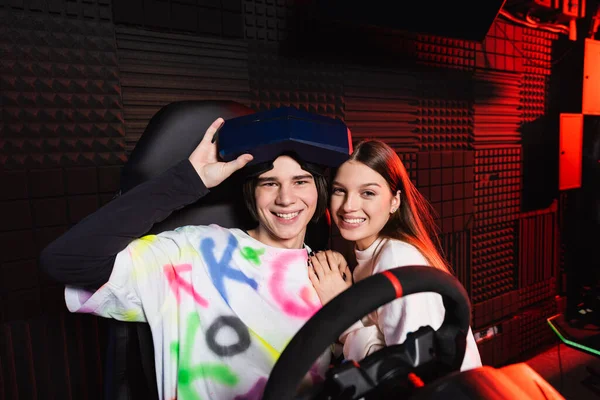 Felizes Amigos Adolescentes Sorrindo Para Câmera Perto Simulador Corrida Carro — Fotografia de Stock