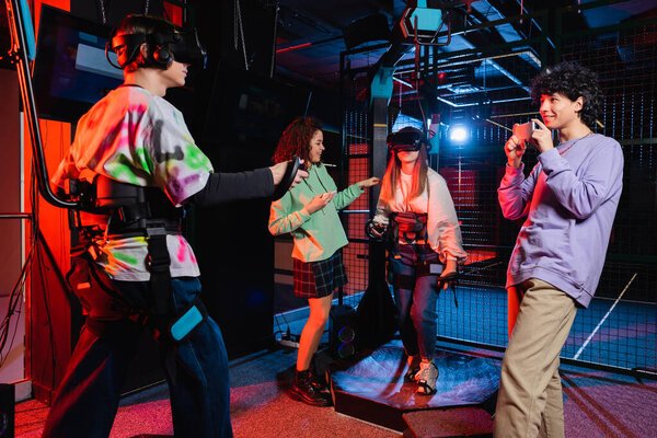 веселый мальчик фотографирует межрасовых подростков, играющих на платформе vr