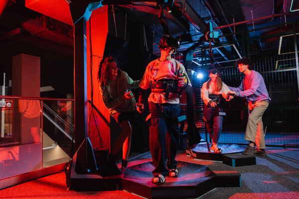 веселые мультиэтнические подростки, глядя на друзей игры в наушниках vr