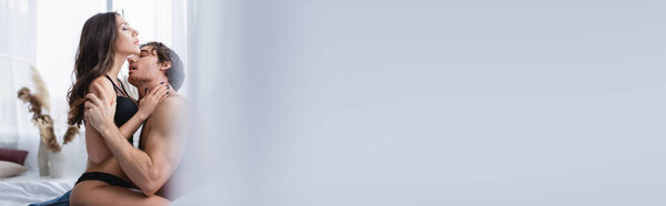 Соблазнительный мужчина целует красивую девушку в постели, баннер 