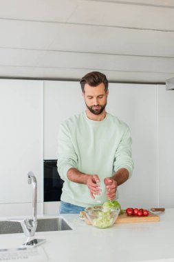 Adam kahvaltıda taze sebzelerden salata hazırlıyor.