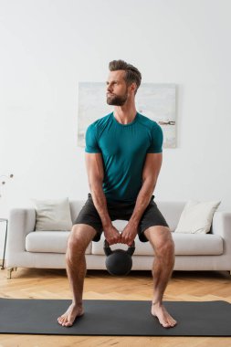 Evde kettlebell ile çıplak ayaklı sporcu eğitimi.