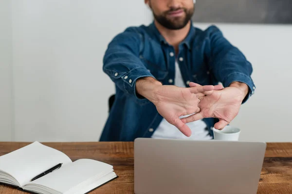 Przycięty Widok Niewyraźne Freelancer Rozciągające Ręce Pobliżu Laptopa Pustego Notebooka — Zdjęcie stockowe