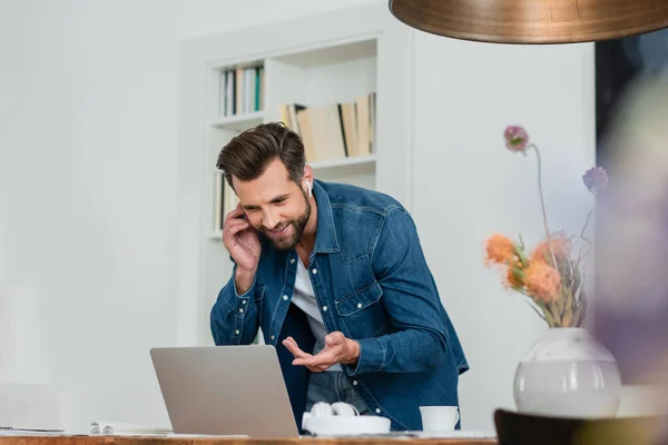 Glimlachende Freelancer Wijzen Naar Laptop Tijdens Het Praten Mobiele Telefoon — Stockfoto