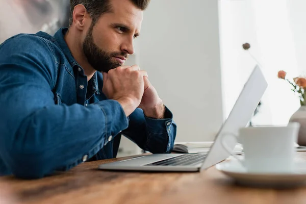 Pensive Freelancer Werken Buurt Van Laptop Wazig Voorgrond — Stockfoto