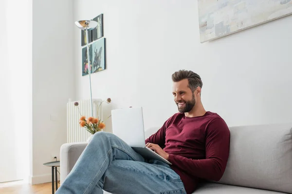 Usměvavý Muž Sedící Pohovce Píšící Notebooku — Stock fotografie