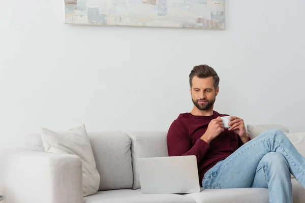 Homem Com Xícara Café Sentado Sofá Perto Laptop — Fotografia de Stock