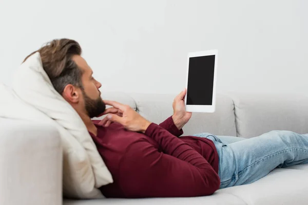 大人の男は自宅のソファで休んでいる間にデジタルタブレットを持って — ストック写真