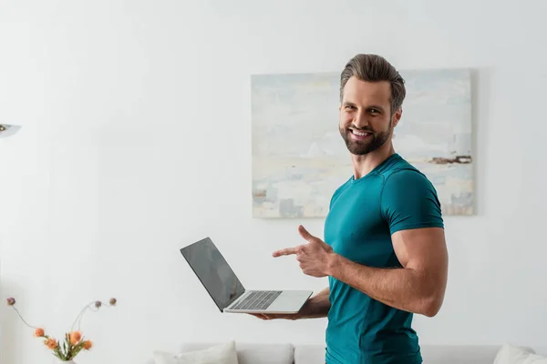Щасливий Чоловік Вказує Пальцем Ноутбук Посміхаючись Камеру — стокове фото