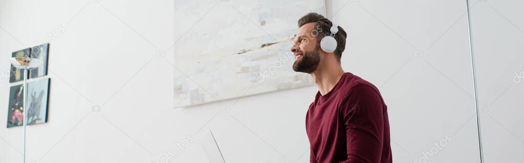 smiling man looking away while listening music in wireless headphones, banner