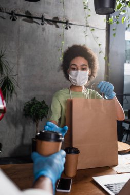 Plastik eldivenli bulanık barista kafe 'deki iş arkadaşına kahve veriyor. 