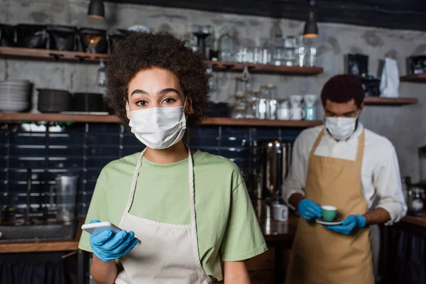 Africký Americký Barista Lékařské Masce Latexové Rukavici Držící Mobilní Telefon — Stock fotografie