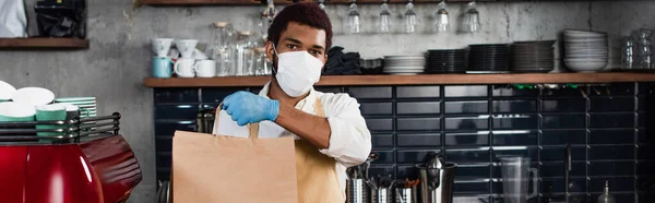 African American Barista Medical Mask Holding Paper Bag Cafe Banner — Stock Photo, Image