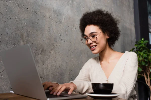 Positiv Afrikansk Amerikansk Distansarbetare Med Laptop Nära Suddig Kopp Caféet — Stockfoto