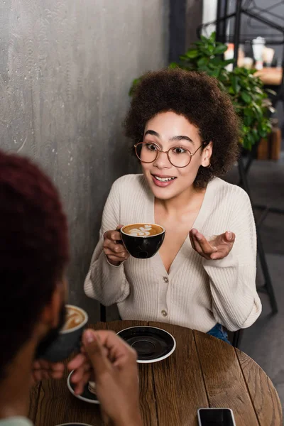 Glimlachende Afrikaan Amerikaanse Vrouw Met Koffie Praten Met Wazig Vriendje — Stockfoto