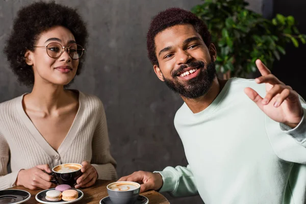 Smiling African American Man Looking Away Girlfriend Coffee Macaroons Cafe — Stock Photo, Image