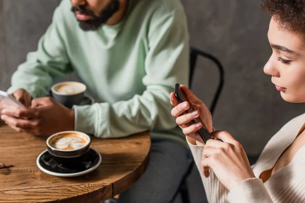 Mujer Afroamericana Usando Teléfono Celular Cerca Café Borroso Novio Cafetería — Foto de Stock