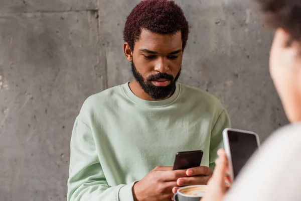 Africano Americano Homem Usando Celular Perto Xícara Café Namorada Borrada — Fotografia de Stock