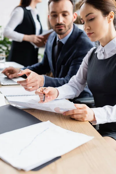 Zakenvrouw Wijst Naar Document Buurt Van Collega Wazige Achtergrond — Stockfoto