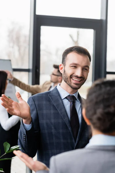 笑顔のビジネスマンがオフィスで同僚をぼやけて話す — ストック写真