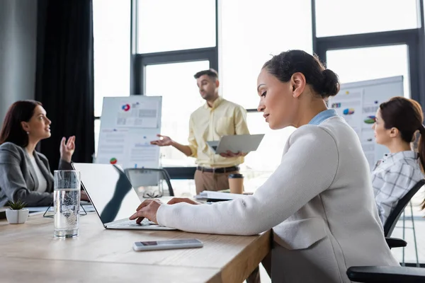 African American Businesswoman Using Laptop Glass Water Blurred Colleagues — Stock Photo, Image