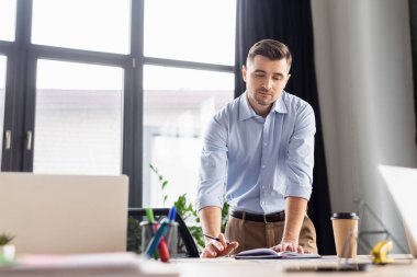 İş adamı dizüstü bilgisayarların yanında defter ve kahve arıyor. 