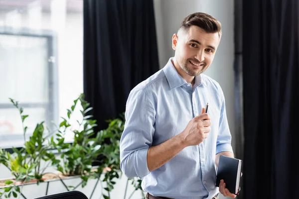 Vrolijke Zakenman Met Pen Notebook Zoek Naar Camera Kantoor — Stockfoto