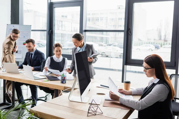 Affärskvinna Med Papper Nära Kaffe Dator Och Multietniska Kollegor Kontoret — Stockfoto