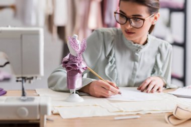 Dikiş makinesinin yanındaki manken ve bulanık tasarımcı 