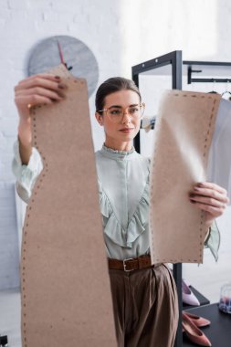 Gözlüklü tasarımcı bulanık dikiş desenleri tutuyor 